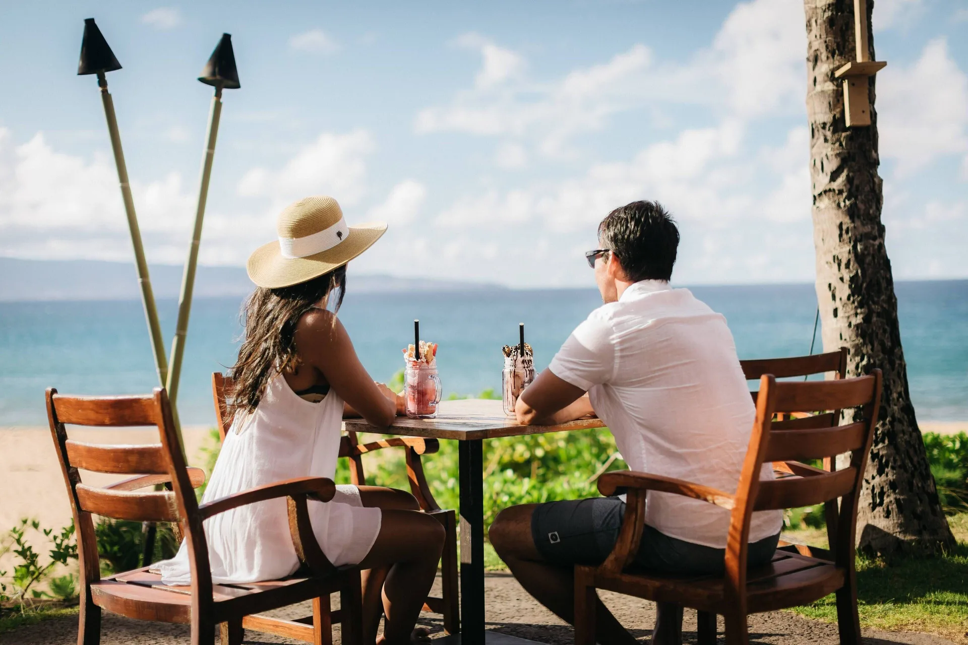 Two guests sit with drinks overlooking the ocean at The Ritz-Carlton Maui, Kapalua.