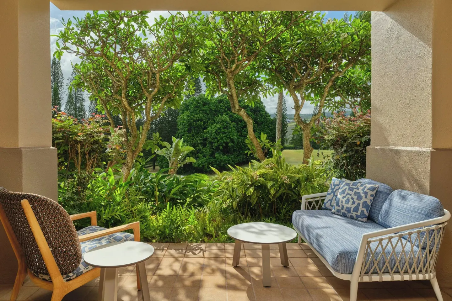 Patio seating framed by tropical garden plants at The Ritz-Carlton Maui, Kapalua.