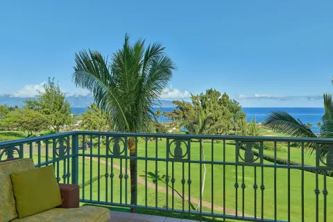 Suite balcony with lounge chair and ocean view at The Ritz-Carlton Maui, Kapalua.