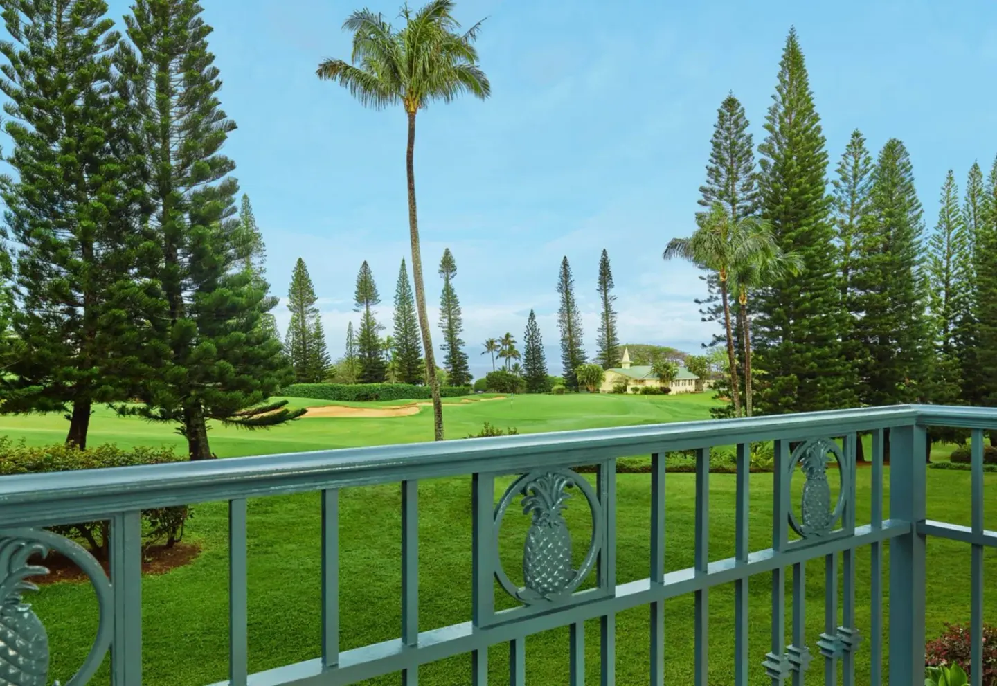 Deluxe Room partial ocean view balcony at The Ritz-Carlton Maui, Kapalua overlooking lawns and tall trees.