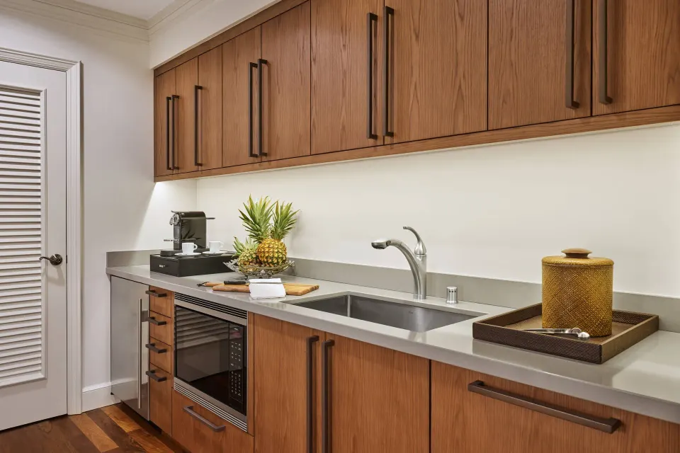 Royal Suite Oceanfront kitchenette at The Ritz-Carlton Maui, Kapalua with sink, cabinets, and fruit.