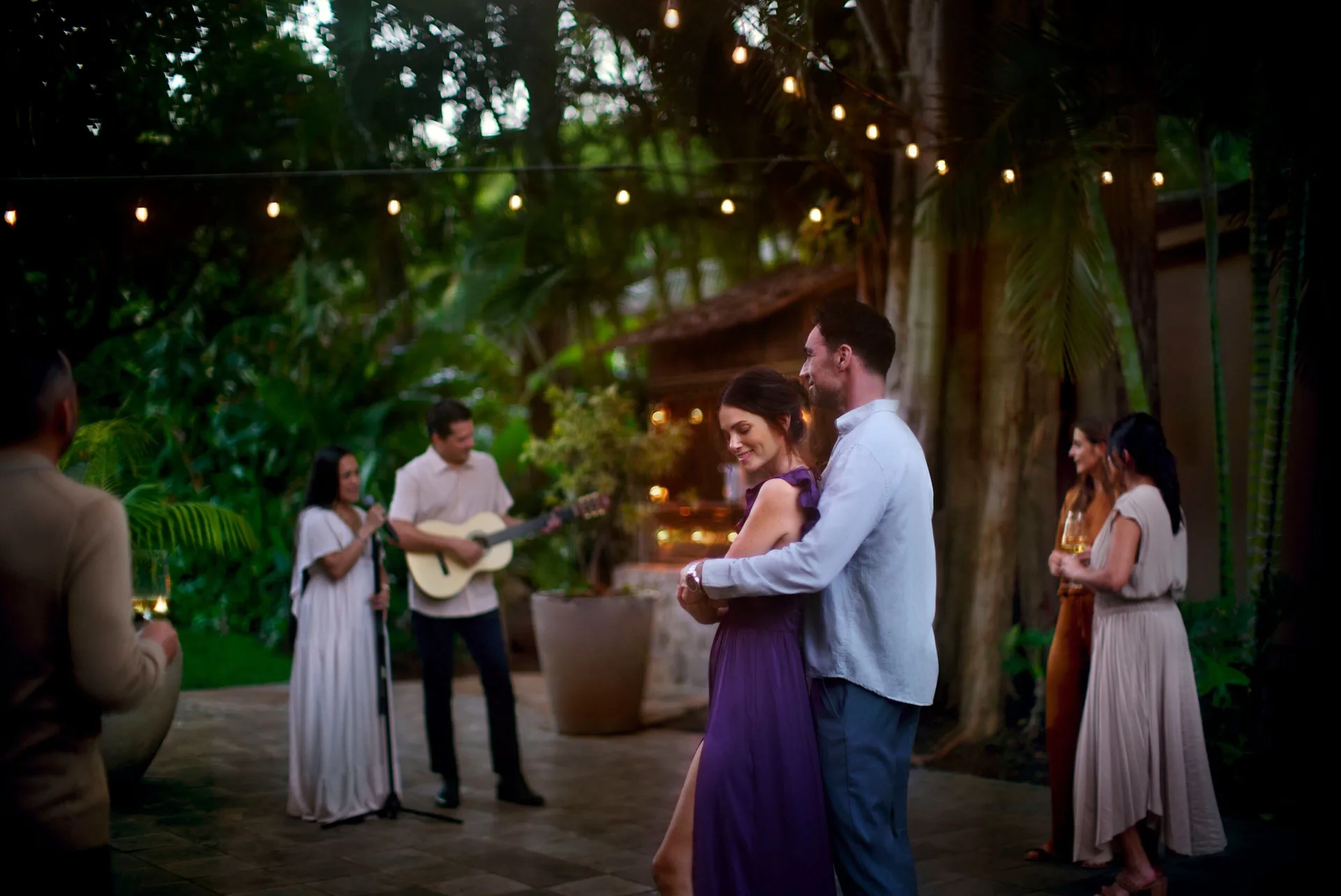 Guests dance under string lights in a garden at The Ritz-Carlton Maui, Kapalua.