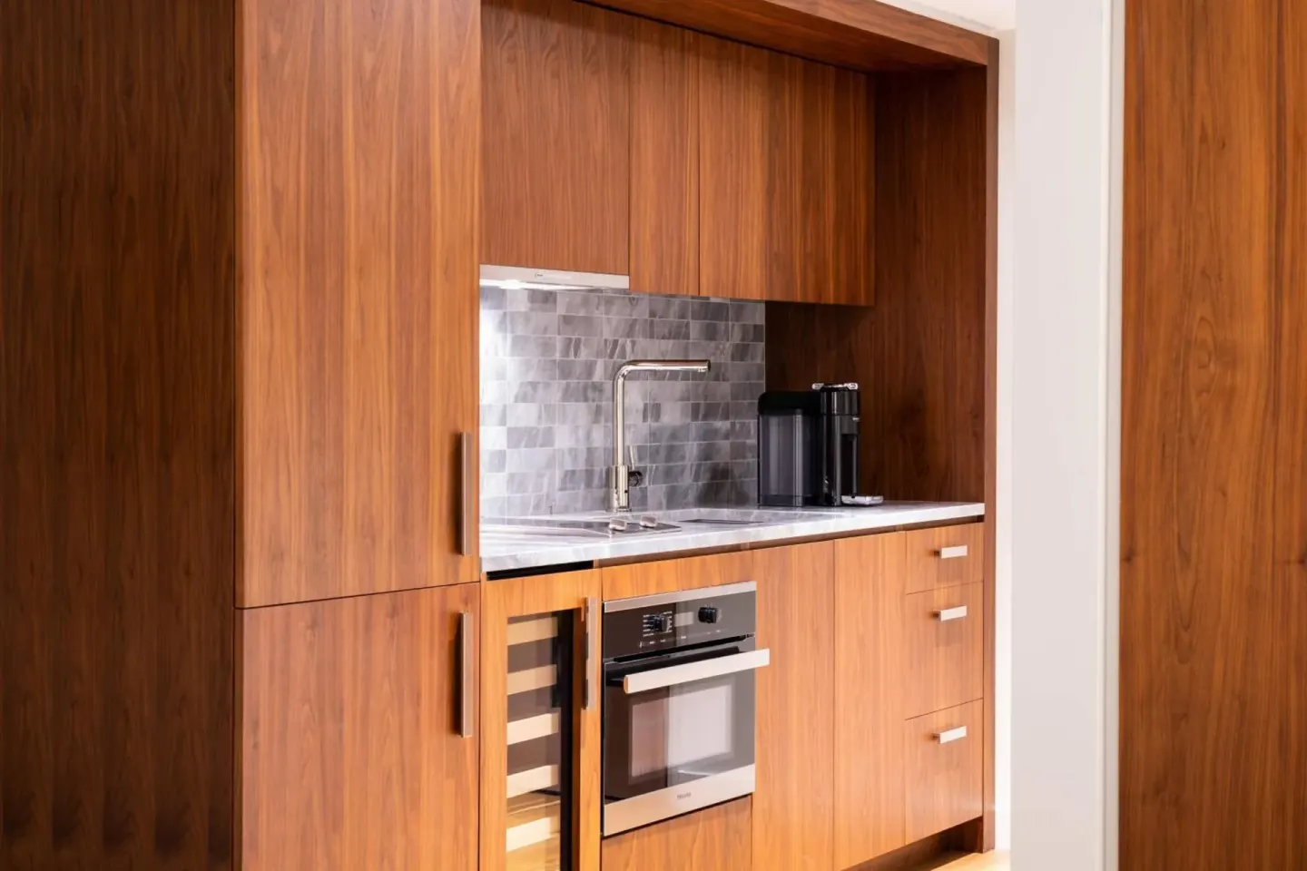 Compact wood kitchenette with sink and oven at The Ritz-Carlton Residences, Waikiki Beach.
