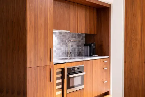 Compact wood kitchenette with sink and oven at The Ritz-Carlton Residences, Waikiki Beach.