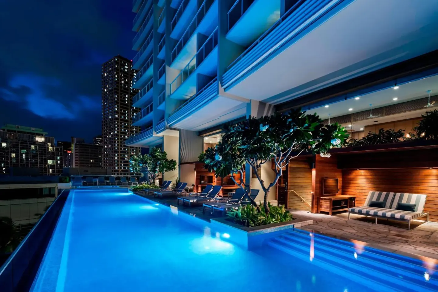 Nighttime pool deck with loungers at The Ritz-Carlton Residences, Waikiki Beach.