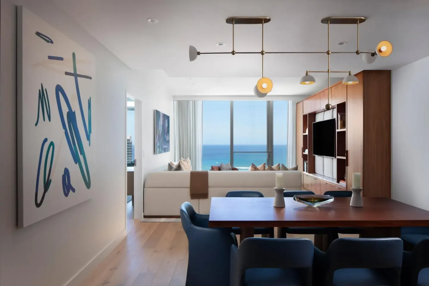Ocean-view dining and living room at The Ritz-Carlton Residences, Waikiki Beach with artwork and TV wall.