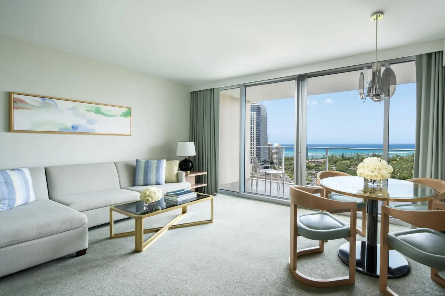 Living and dining area with an ocean-view balcony at The Ritz-Carlton Residences, Waikiki Beach.