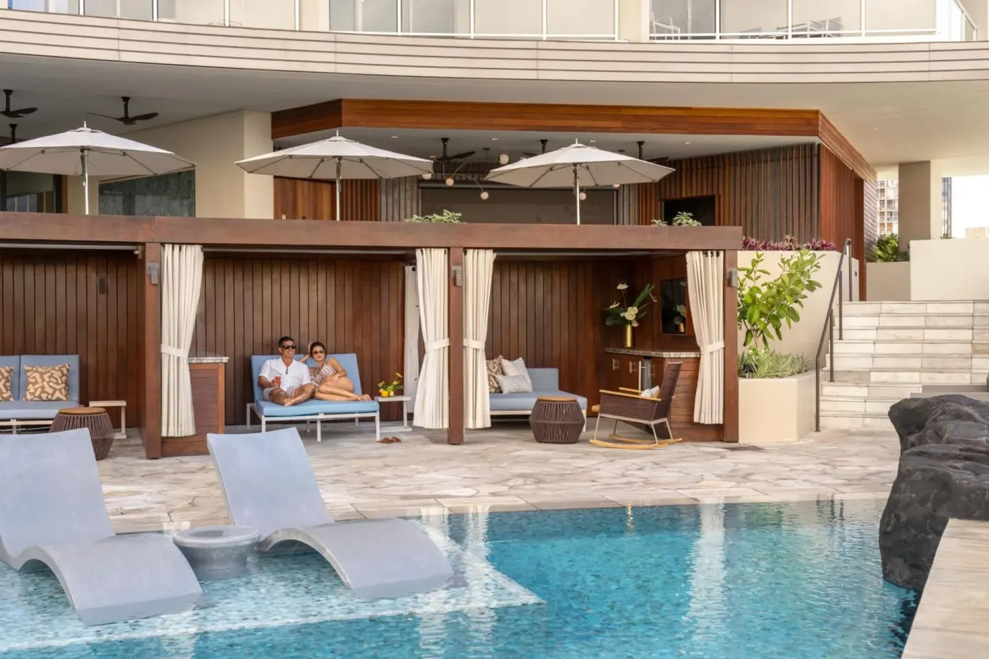 Pool deck with cabanas and in-water loungers at The Ritz-Carlton Residences, Waikiki Beach.