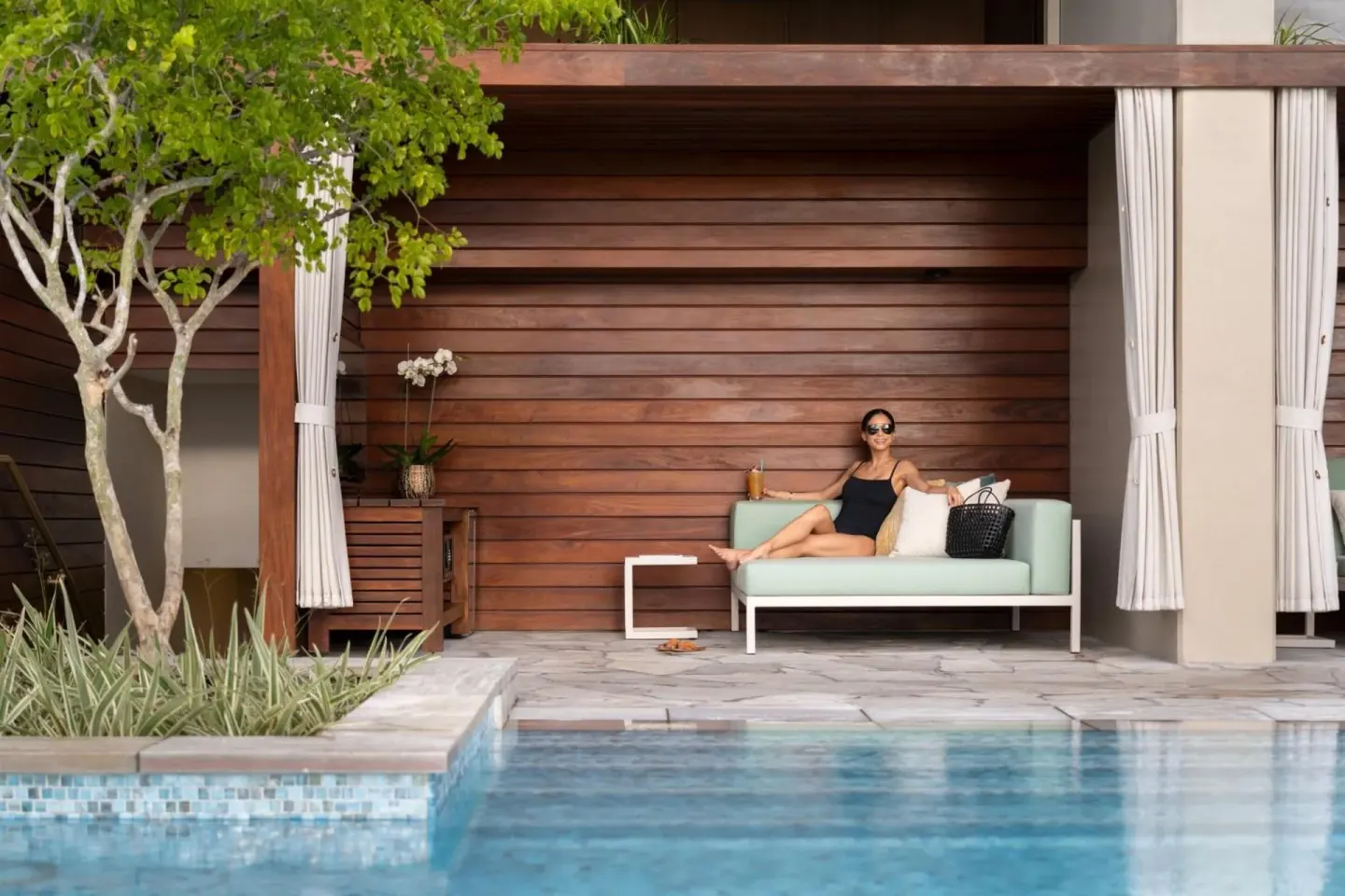 Guest reclining in a poolside cabana at The Ritz-Carlton Residences, Waikiki Beach.