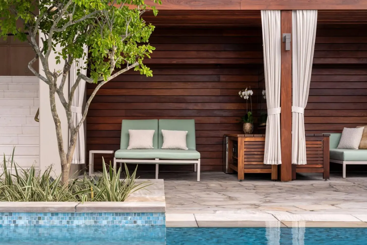 Poolside cabana with mint lounge seating and curtains at The Ritz-Carlton Residences, Waikiki Beach.