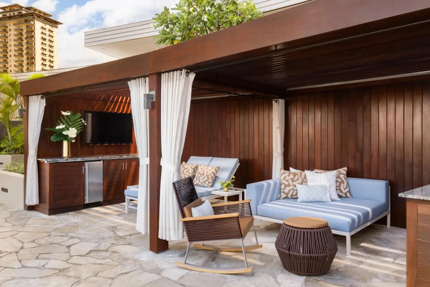 Private cabana with blue loungers and curtains at The Ritz-Carlton Residences, Waikiki Beach.