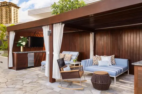 Private cabana with blue loungers and curtains at The Ritz-Carlton Residences, Waikiki Beach.
