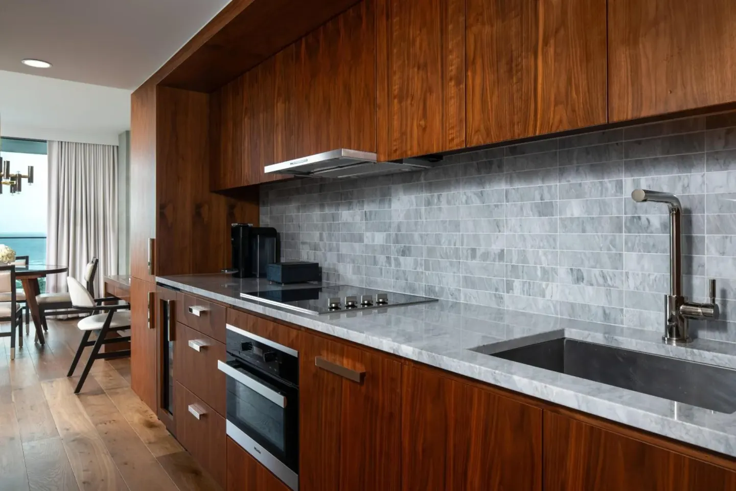 Suite kitchenette with wood cabinetry and gray tile backsplash at The Ritz-Carlton Residences, Waikiki Beach.