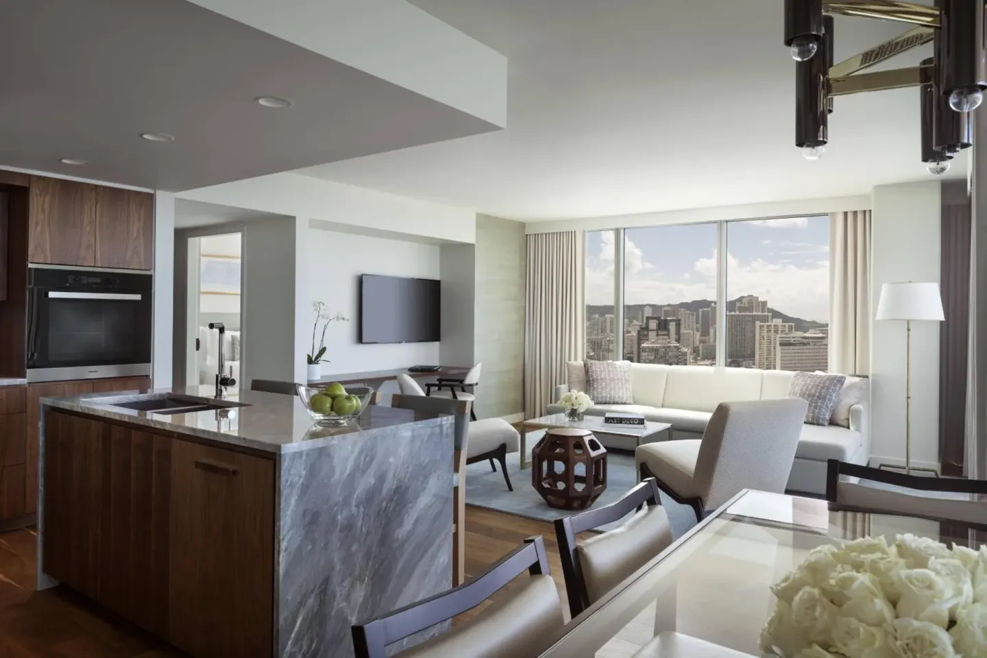 Suite living area with kitchen, dining table, sofa, and city view at The Ritz-Carlton Residences, Waikiki Beach.