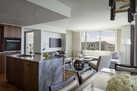 Suite living area with kitchen, dining table, sofa, and city view at The Ritz-Carlton Residences, Waikiki Beach.