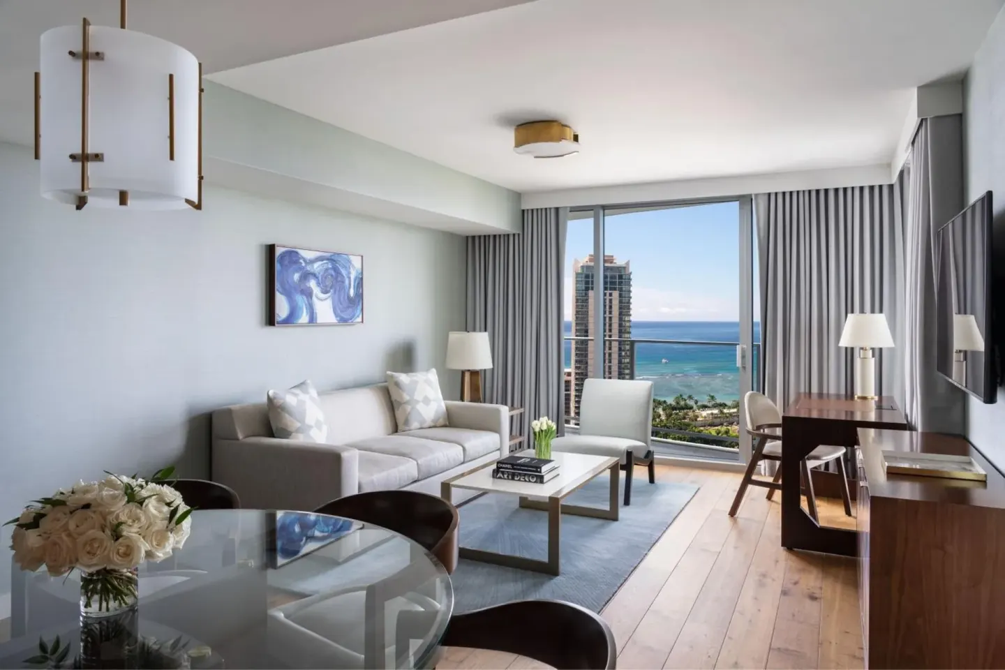 Suite living room with sofa, dining table, desk, and ocean view at The Ritz-Carlton Residences, Waikiki Beach.