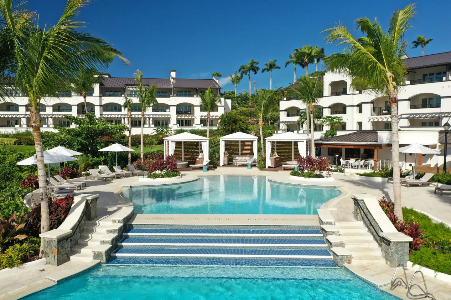 Resort pool with cabanas, umbrellas, palms, and guest buildings at The Ritz-Carlton, St. Thomas.