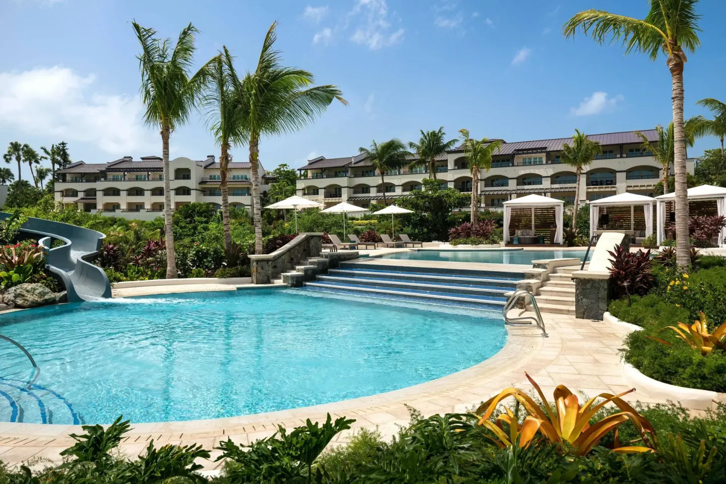 Resort pool with waterslide, palms, and cabanas at The Ritz-Carlton, St. Thomas.