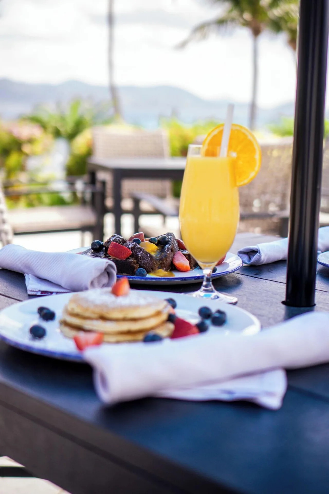 Breakfast plates and orange juice on an outdoor table at The Ritz-Carlton, St. Thomas.