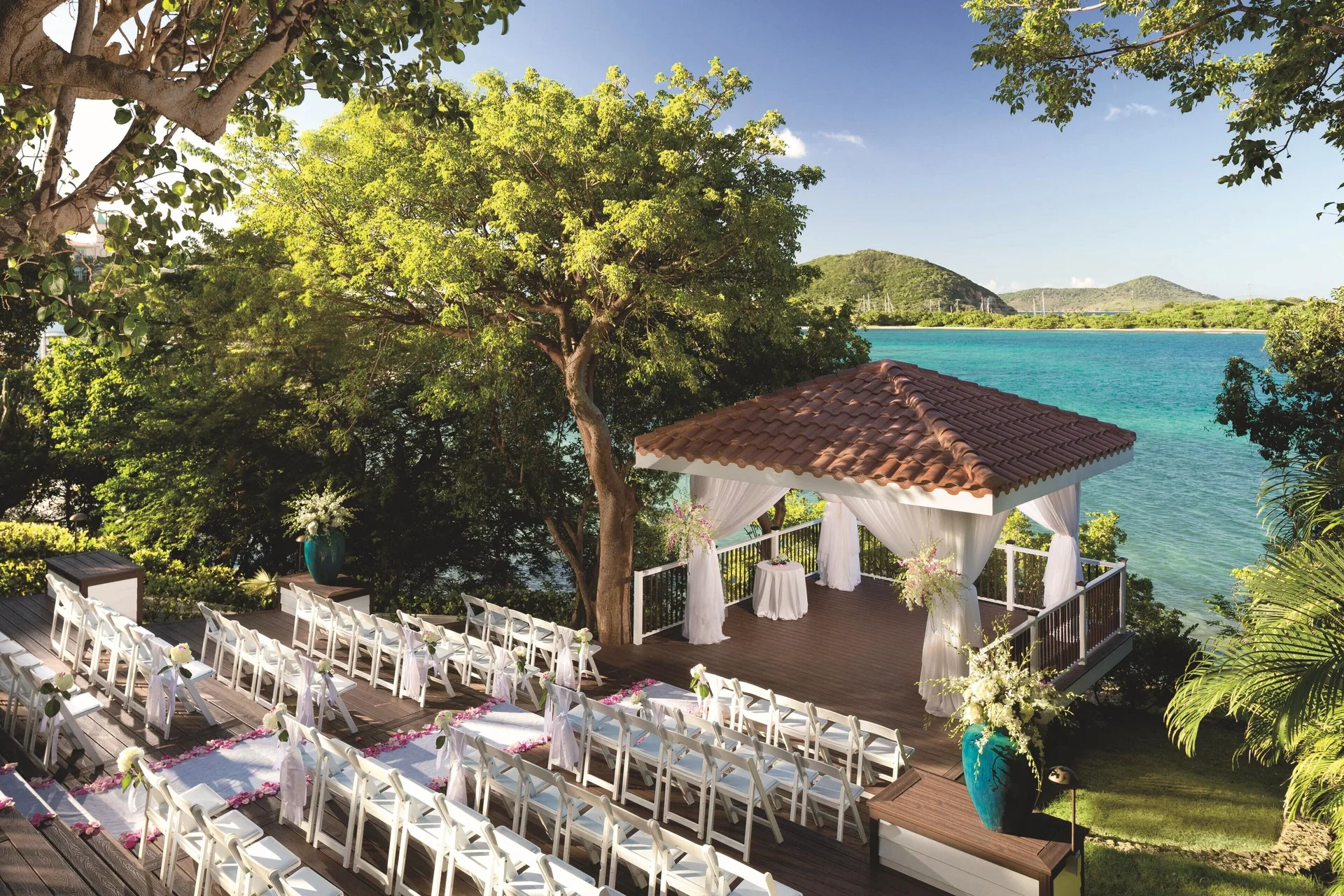 Elevated waterfront wedding deck at The Ritz-Carlton, St. Thomas with rows of white chairs and a gazebo.