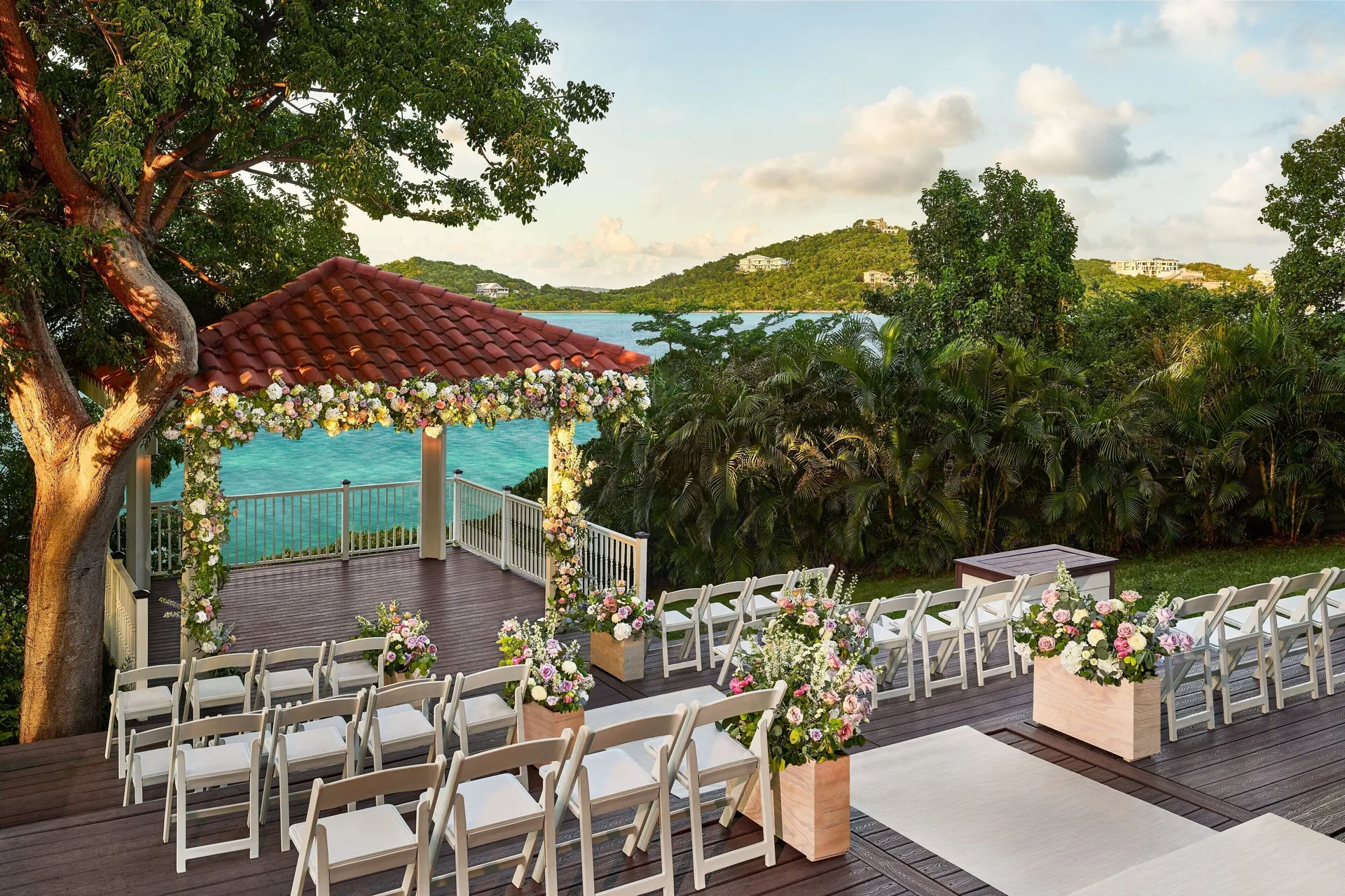 Floral wedding ceremony deck at The Ritz-Carlton, St. Thomas overlooking turquoise water and hills.