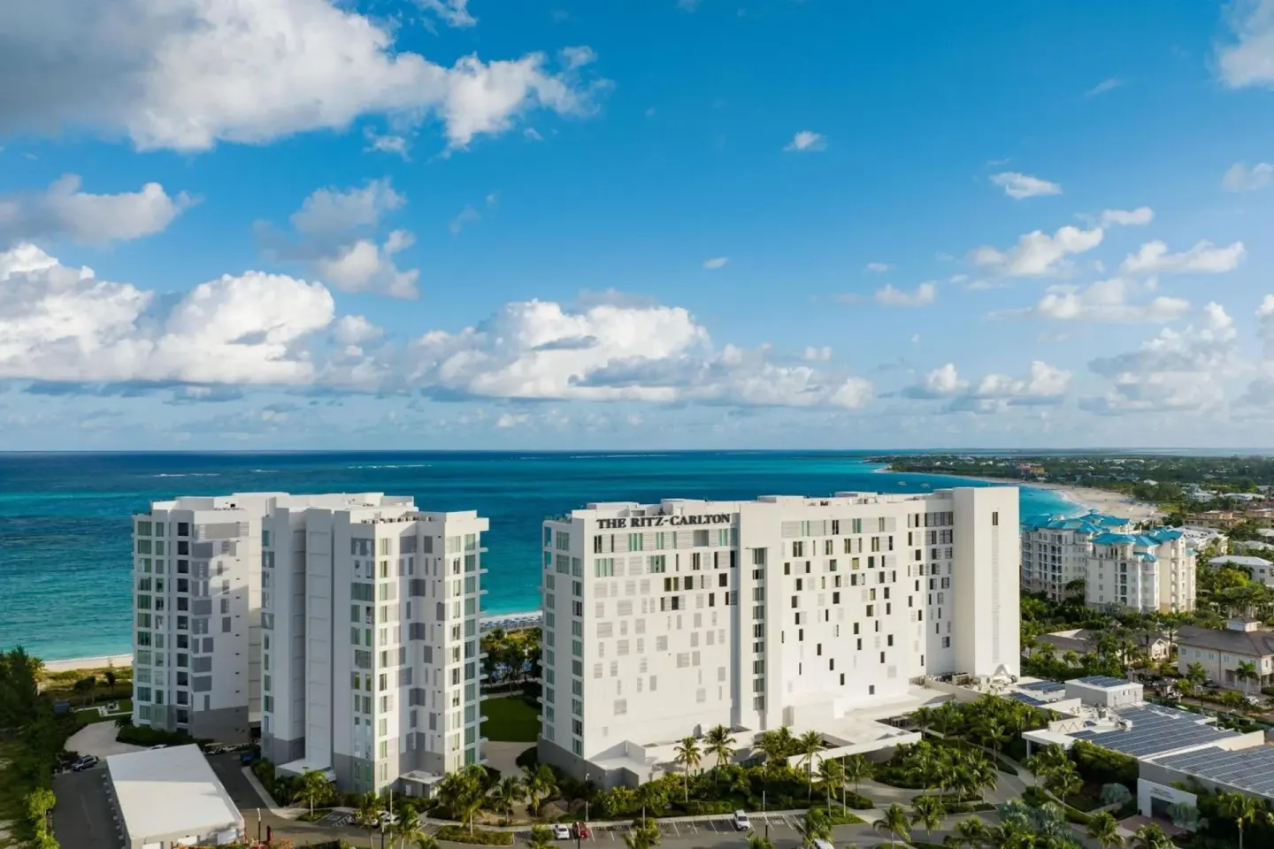 Aerial view of The Ritz-Carlton, Turks & Caicos buildings beside the ocean under a blue sky.