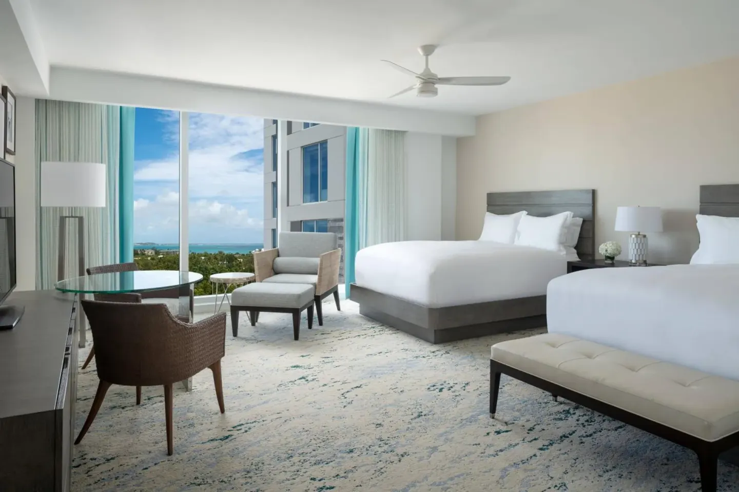 Two queen beds and ocean-facing windows in a guest room at The Ritz-Carlton, Turks & Caicos.