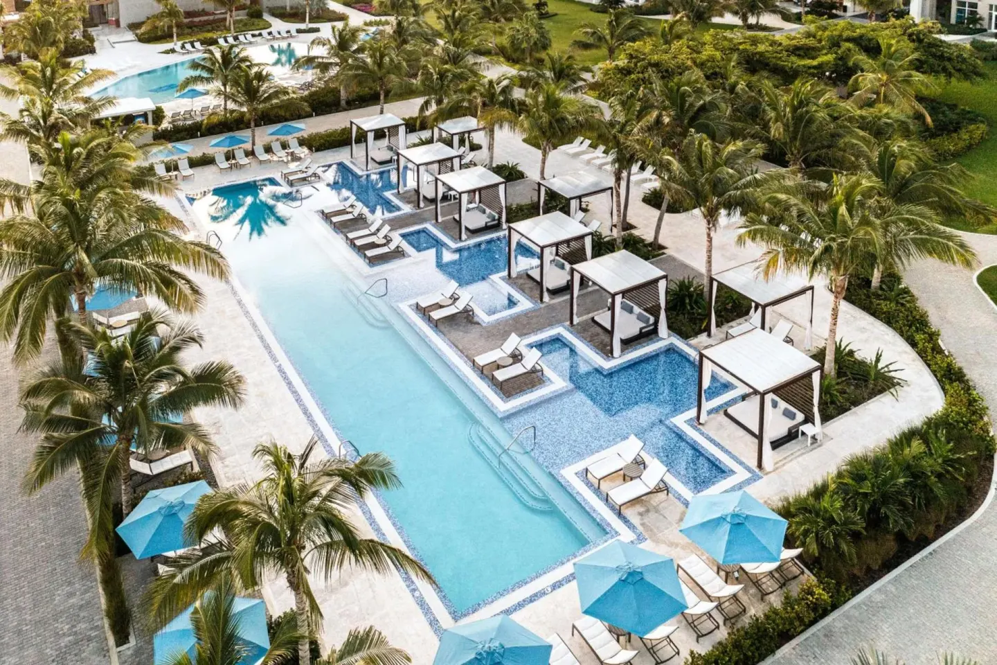 Aerial view of the resort pool with cabanas and palms at The Ritz-Carlton, Turks & Caicos.