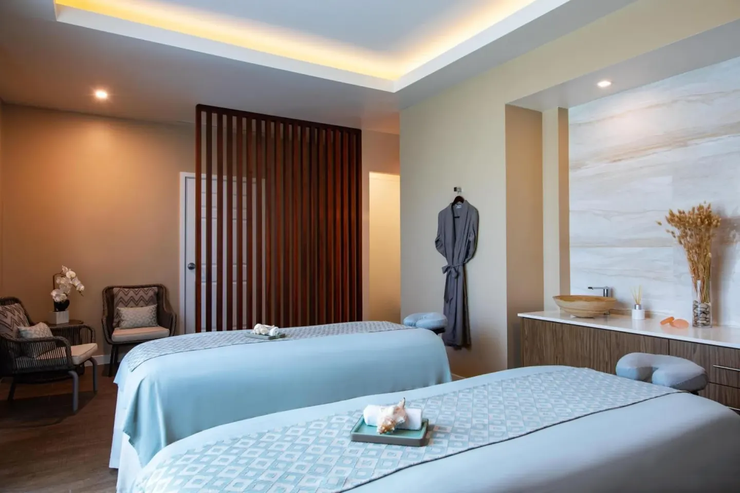Spa treatment room at The Ritz-Carlton, Turks & Caicos with two massage tables, seating, and a vanity area.
