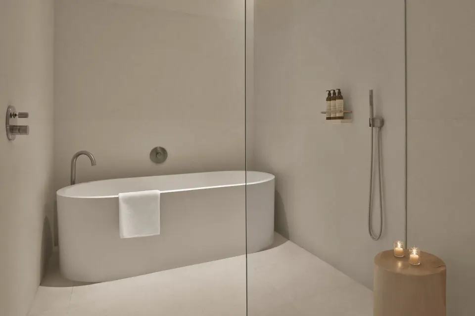 Minimal bathroom at The Riviera Maya EDITION At Kanai with soaking tub and glass shower.