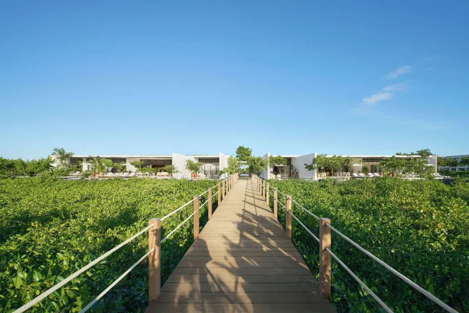 Wooden boardwalk crosses mangroves toward resort buildings at The Riviera Maya EDITION At Kanai.