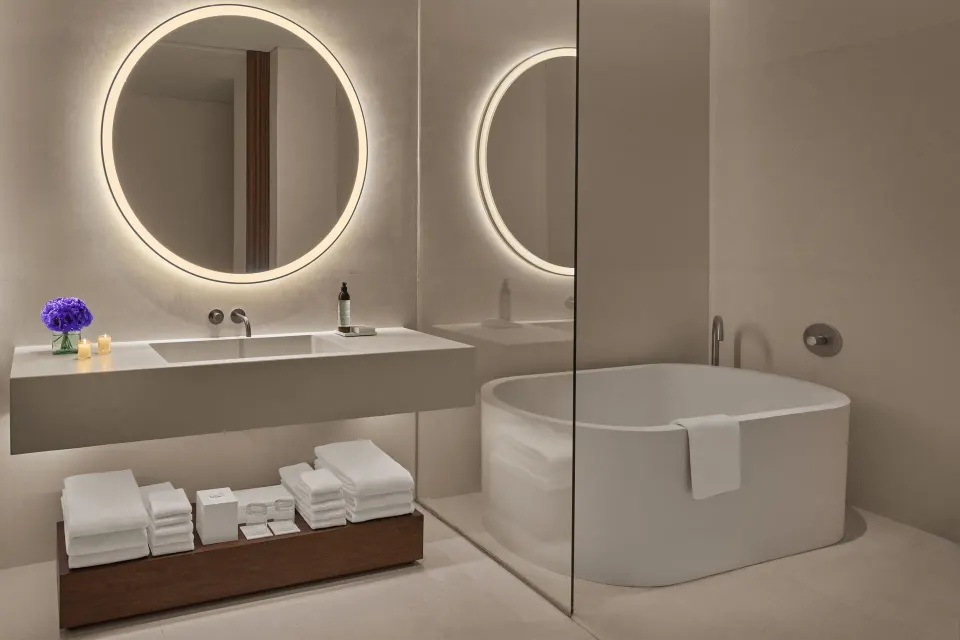 Guest bathroom with soaking tub behind glass at The Riviera Maya EDITION At Kanai.