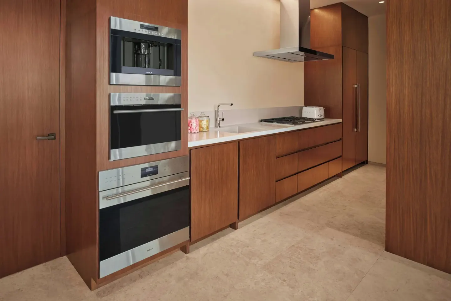 Wood-paneled guest kitchen with built-in appliances at The Riviera Maya EDITION At Kanai.