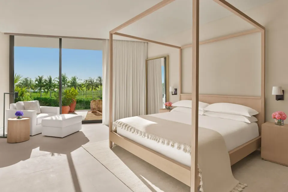 King-bed guest room at The Riviera Maya EDITION At Kanai with lounge area and palm view.