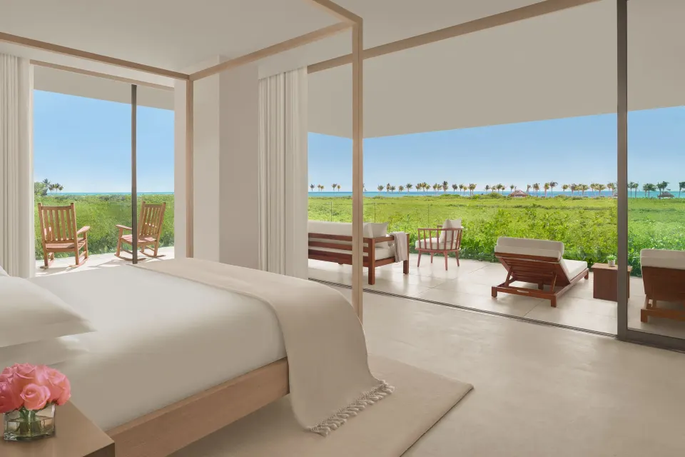 King bedroom opening to a furnished terrace and ocean view at The Riviera Maya EDITION At Kanai.