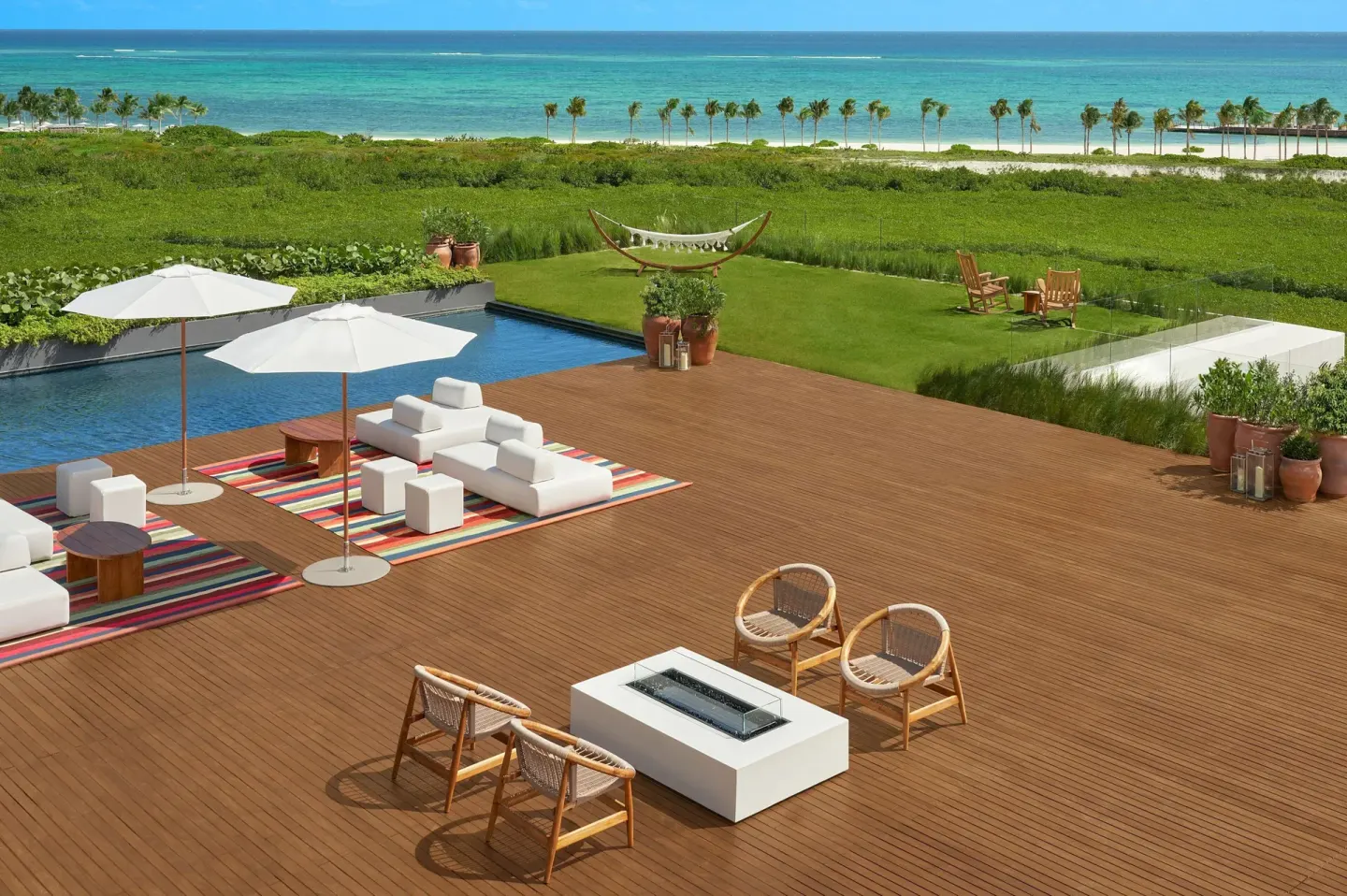Oceanfront deck with pool, seating, and lawn at The Riviera Maya EDITION At Kanai.