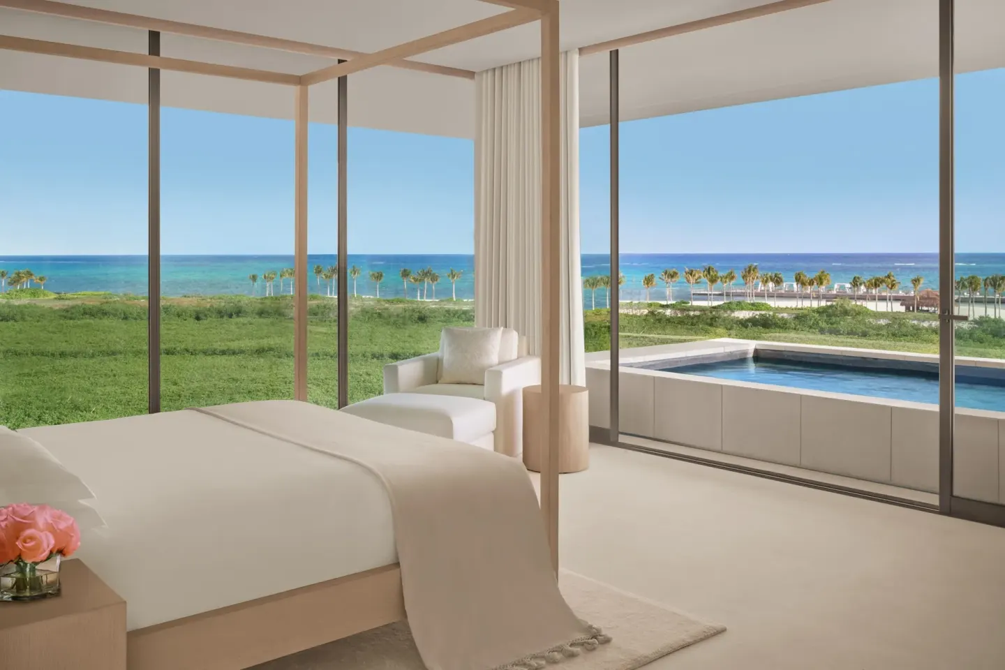 Canopy king bed facing a terrace pool and ocean at The Riviera Maya EDITION At Kanai.