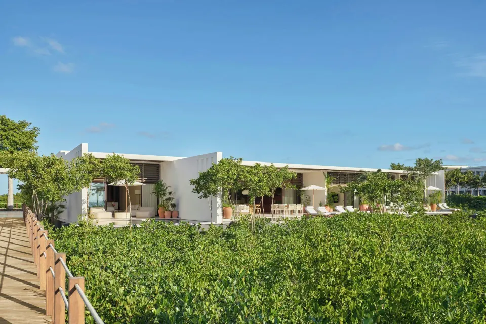 White resort buildings and terraces overlook mangroves at The Riviera Maya EDITION At Kanai.
