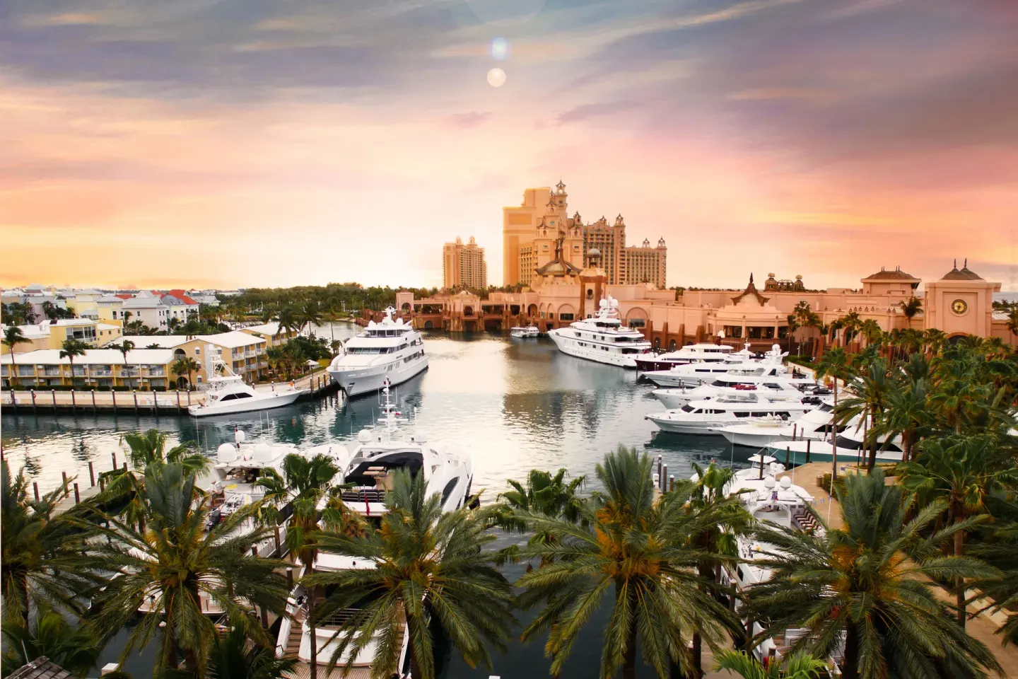 Marina with yachts, palms, and resort towers at sunset at The Royal at Atlantis.