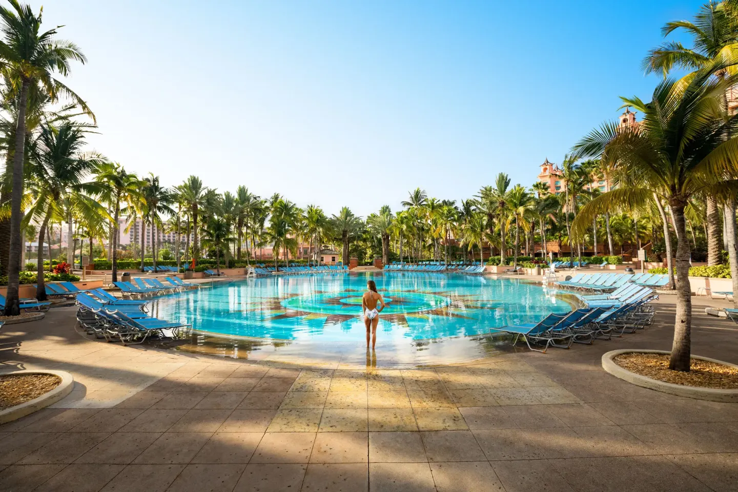 Palm-lined resort pool with blue lounge chairs at The Royal at Atlantis.