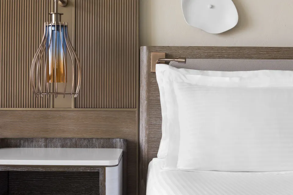 Terrace View room bedside detail with pillow, lamp, and wood paneling at The Royal at Atlantis.