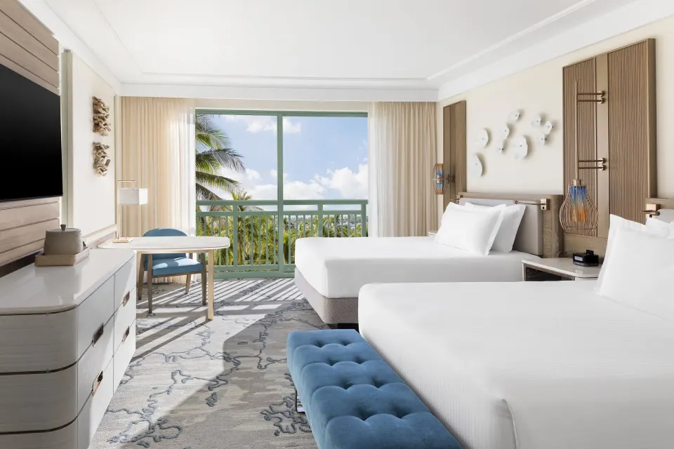 Terrace View guest room with two beds, balcony doors, and palm trees at The Royal at Atlantis.