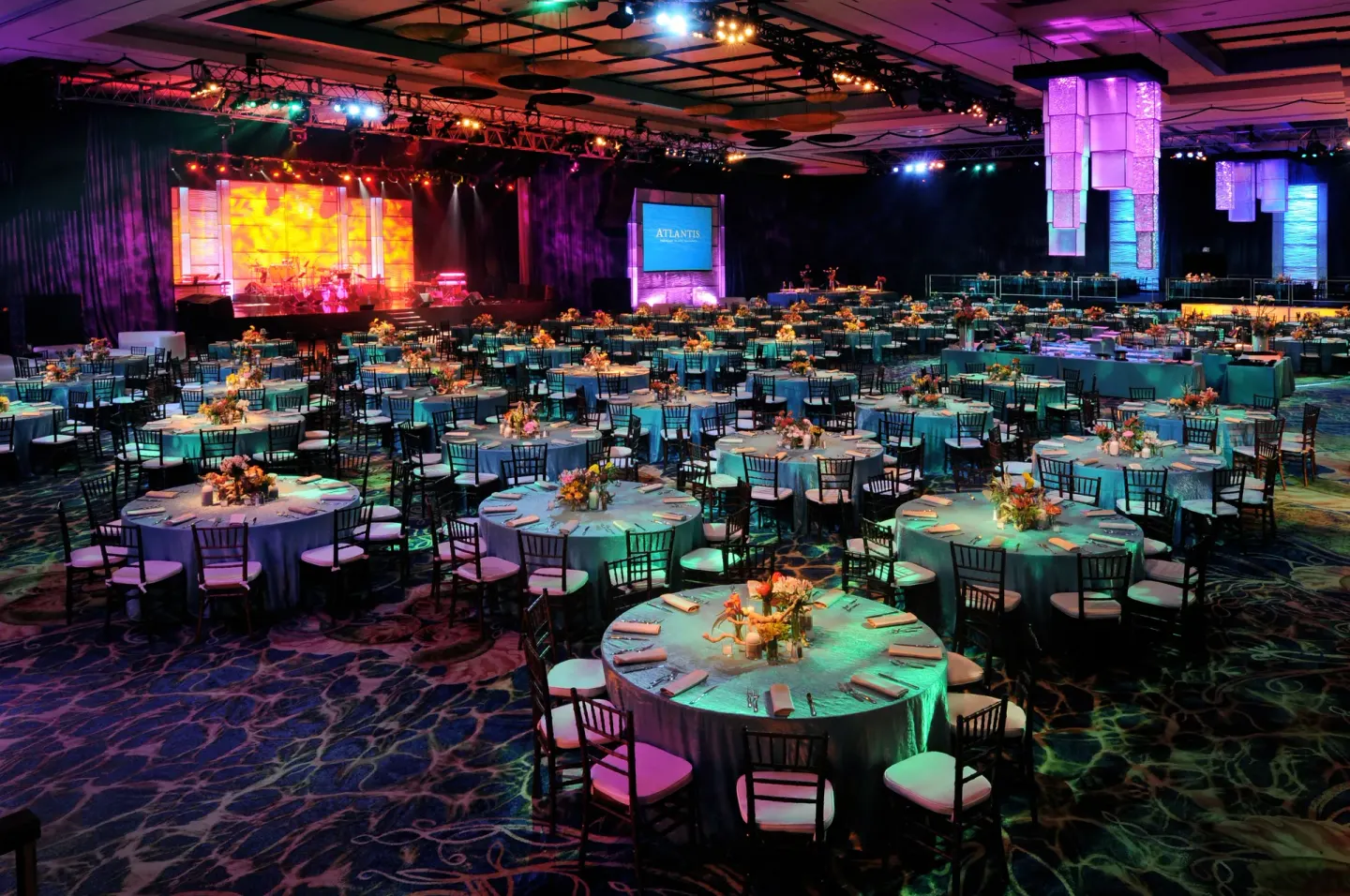 Large banquet room with round tables and stage lighting at The Royal at Atlantis.