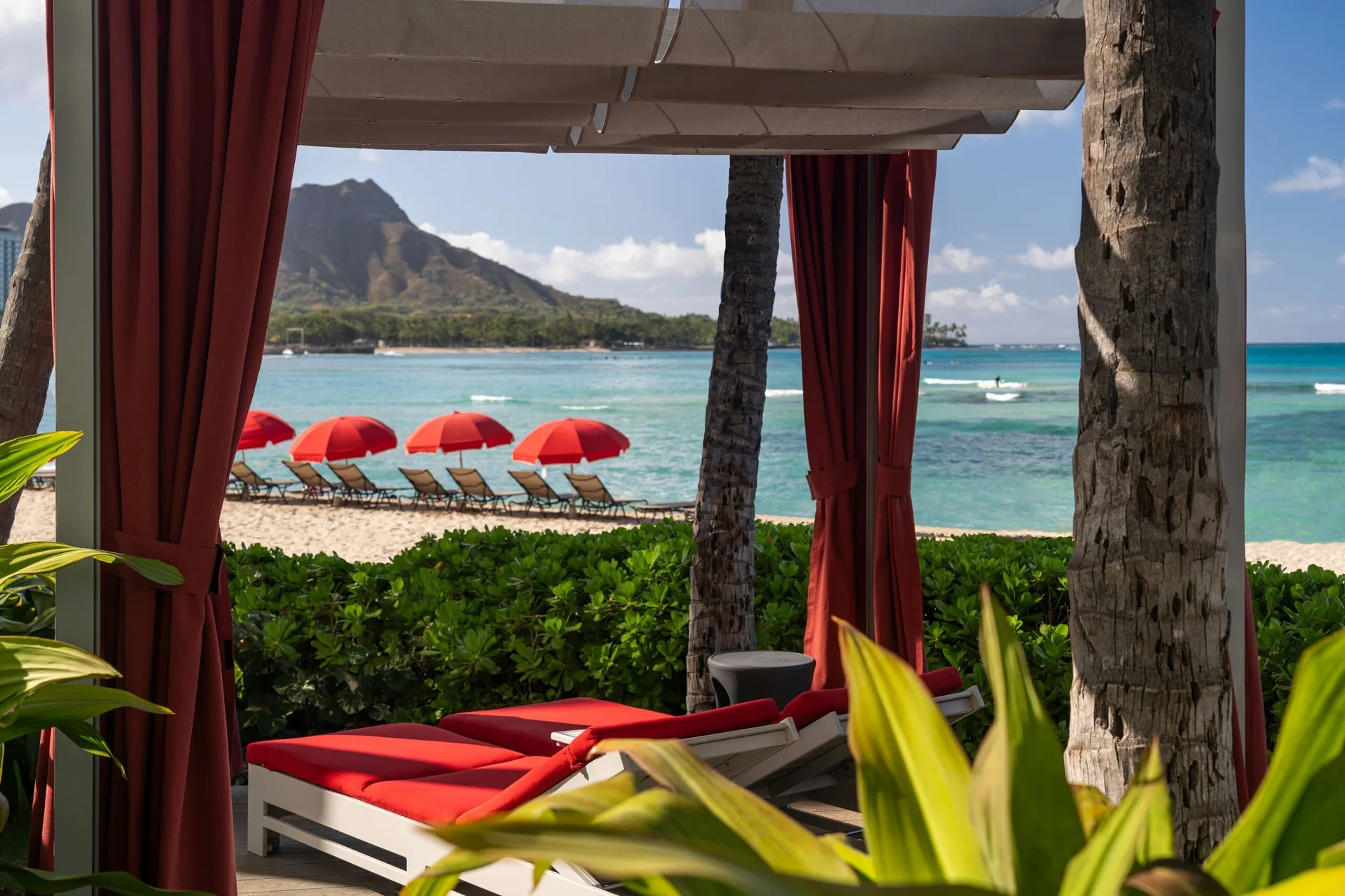 Beach cabana with red curtains overlooking Waikiki and Diamond Head at The Royal Hawaiian, Waikiki.