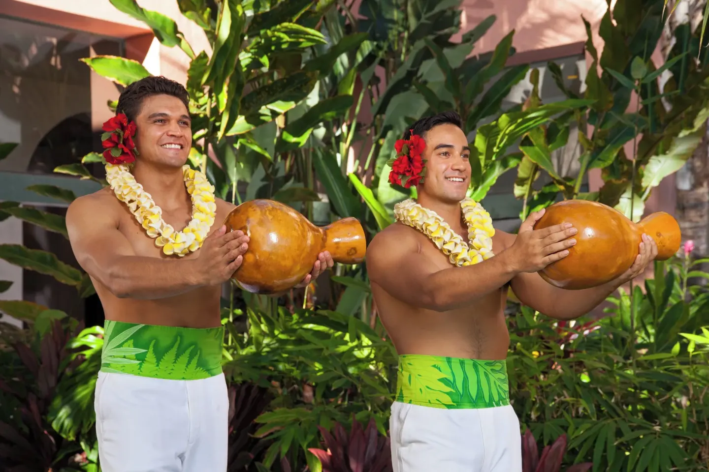 Two performers hold gourd instruments in the garden at The Royal Hawaiian, Waikiki.