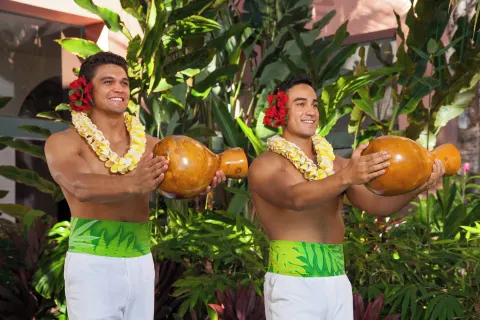 Two performers hold gourd instruments in the garden at The Royal Hawaiian, Waikiki.