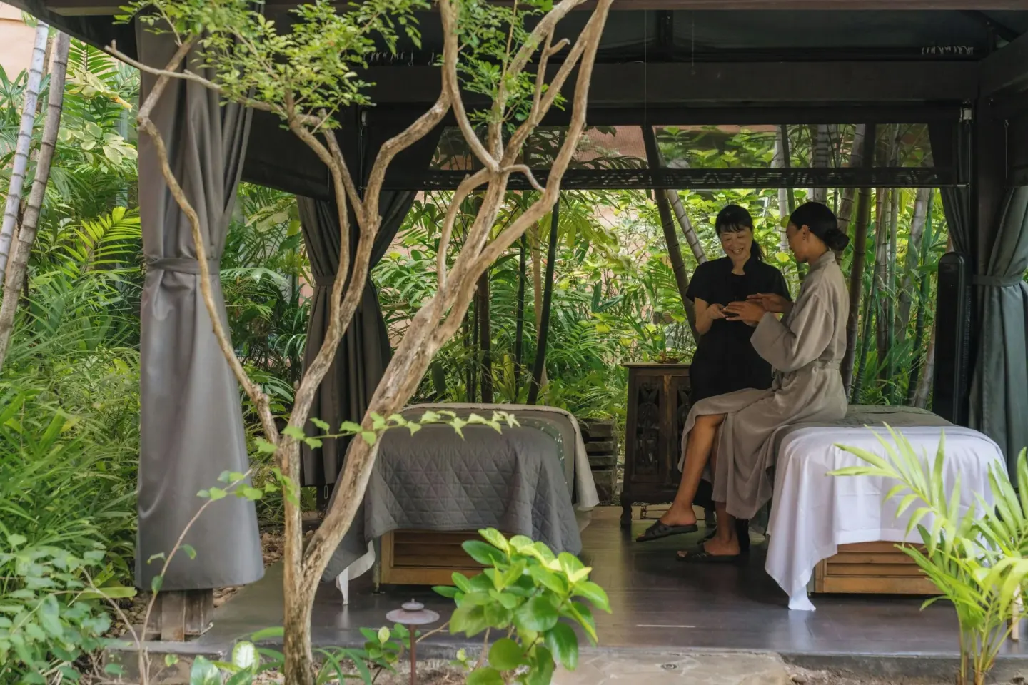 Spa guest and attendant seated in a garden treatment cabana at The Royal Hawaiian, Waikiki.