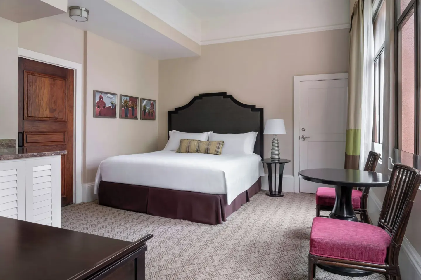 King bed guest room with sitting table and tall windows at The Royal Hawaiian, Waikiki.