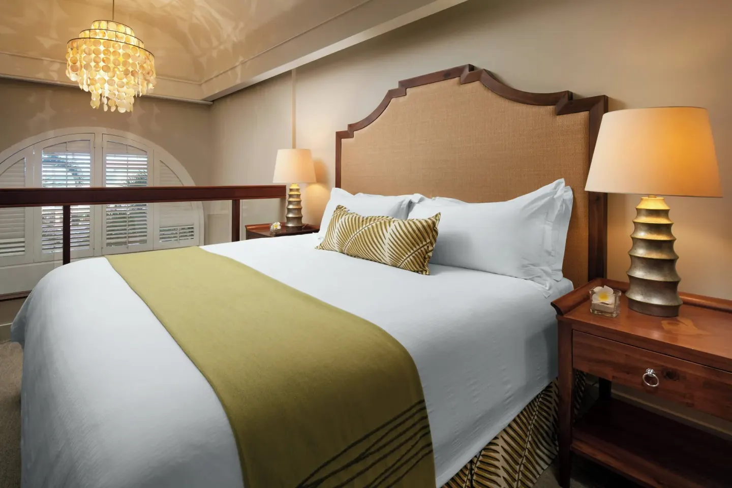 Loft-style king bed with lamps and shutters at The Royal Hawaiian, Waikiki.
