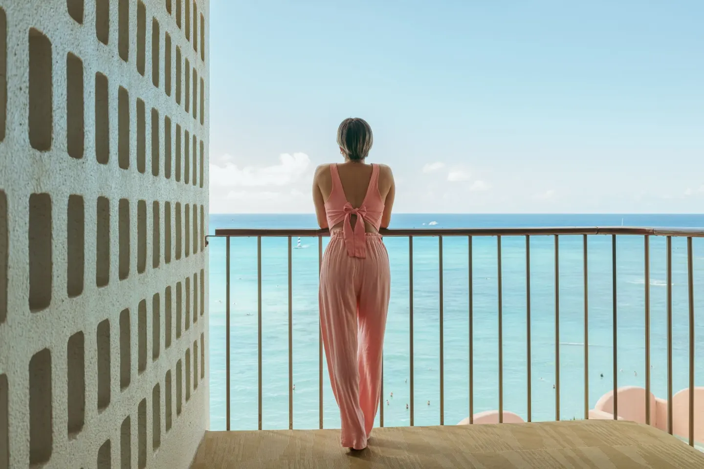 Guest stands on an ocean-view balcony at The Royal Hawaiian, Waikiki.
